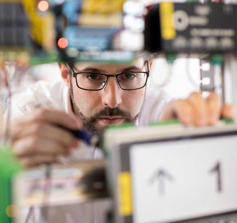 Man wearing glasses working on a circuit board